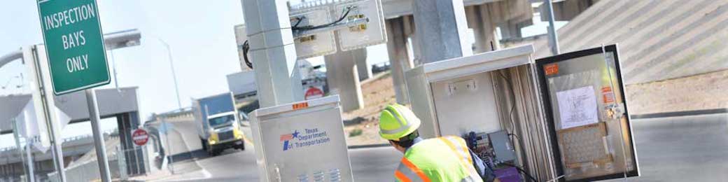 TxDOT worker making adjustments in highway box, next to freeway